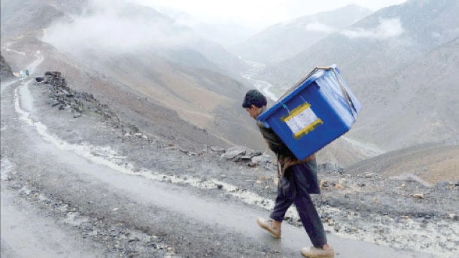 أفغاني يحمل صندوق اقتراع متوجها إلى قريته الواقعة في أعلى جبال شوتول شمال أفغانستان استعدادا للاستحقاق الرئاسي الذي ينطلق اليوم (أ.ف.ب)