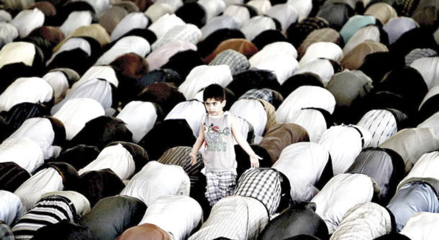 صورة أرشيفية يبدو فيها طفل يقف فيها وسط إيرانيين يؤدون صلاة الجمعة في مسجد جامعة طهران (أ.ف.ب)