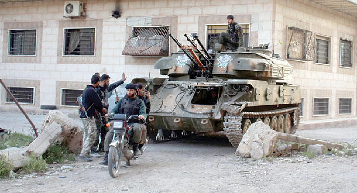 مقاتلون من الجيش السوري الحر بالقرب من مدرعة روسية الصنع استولوا عليها من قوات النظام السوري في الغوطة الشرقية أول من أمس (رويترز)
