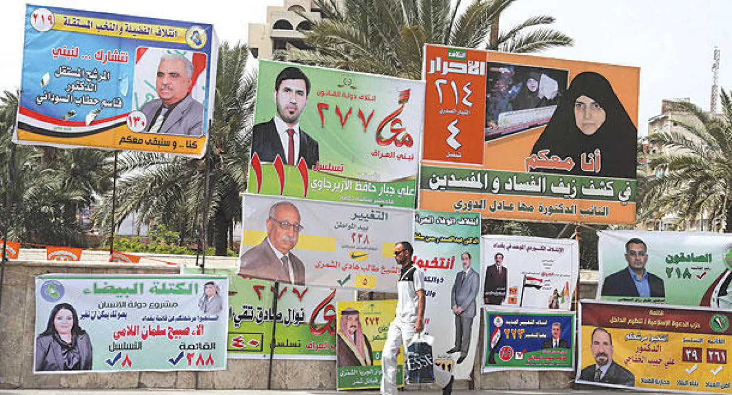 عراقي يمر أمام ملصقات دعائية لمرشحين في الانتخابات البرلمانية في بغداد أمس (أ.ب)