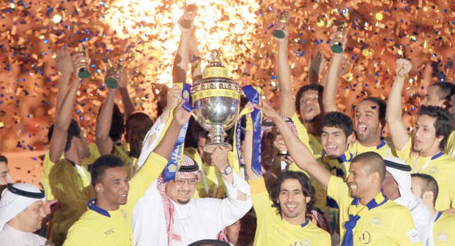 الأمير فيصل بن تركي رئيس النصر يرفع كأس الدوري مع لاعبيه في حفل التتويج (تصوير: علي العريفي)