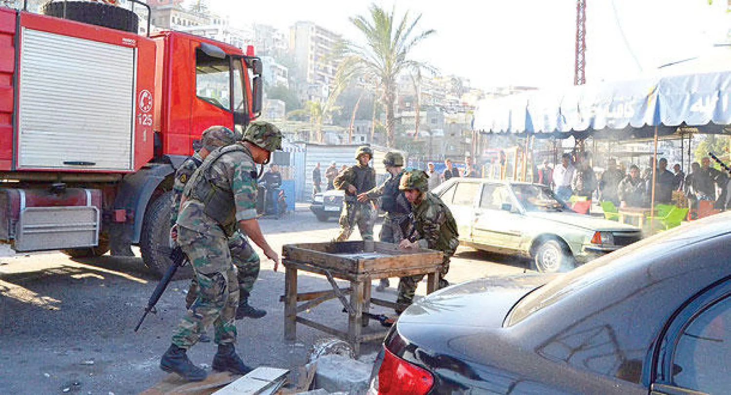 جنود لبنانيون يفتحون طريقا في طرابلس، أمس، أغلقه محتجون على تنفيذ الخطة الأمنية في المدينة (رويترز)