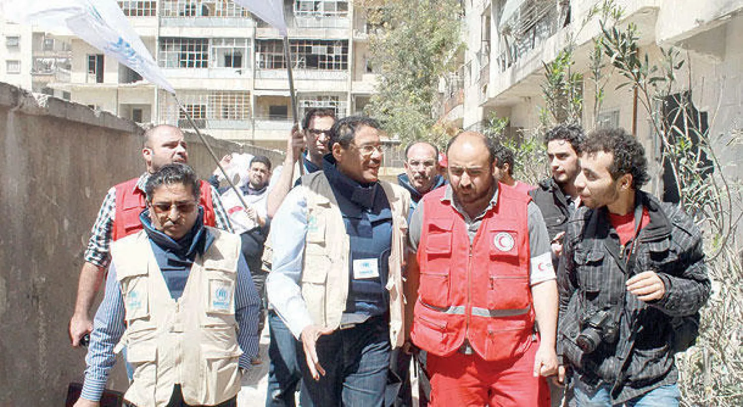 موظفون في الهلال الأحمر السوري والمفوضية السامية لشؤون اللاجئين التابعة للأمم المتحدة يدخلون، أمس، منطقة بستان القصر في حلب، بعد موافقة قوات الحكومة والمعارضة على وقف إطلاق النار لإدخال مساعدات (أ.ف.ب)