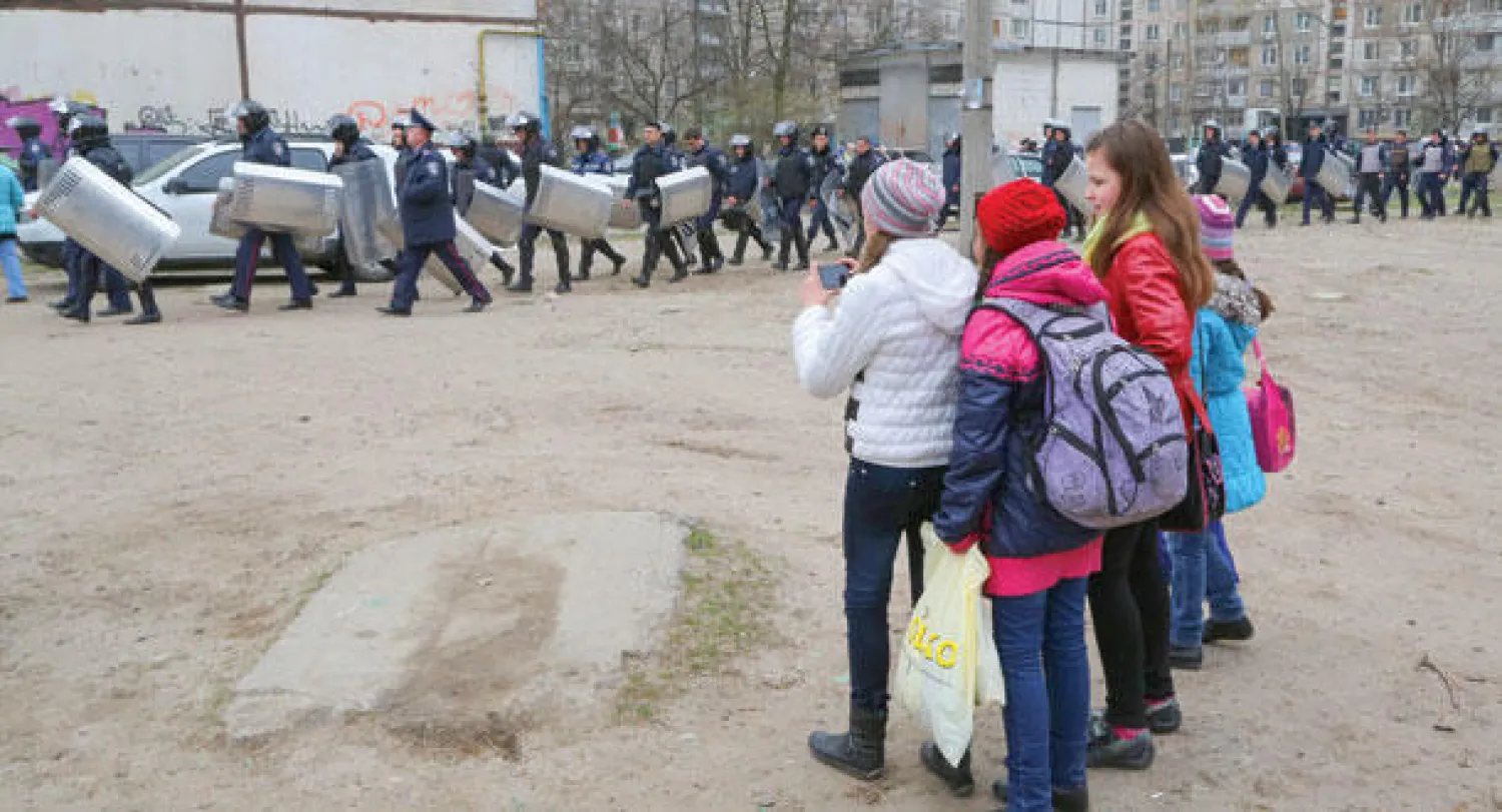 تلميذات يشاهدن عناصر من الشرطة تتقدم في حي كييف بمدينة خاركيف الواقعة شرق أوكرانيا أمس (إ.ب.أ)