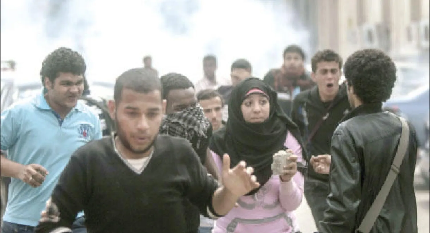 طلاب يفرون من الغاز المسيل للدموع خلال اشتباكات جامعة القاهرة أمس (أ.ف.ب)