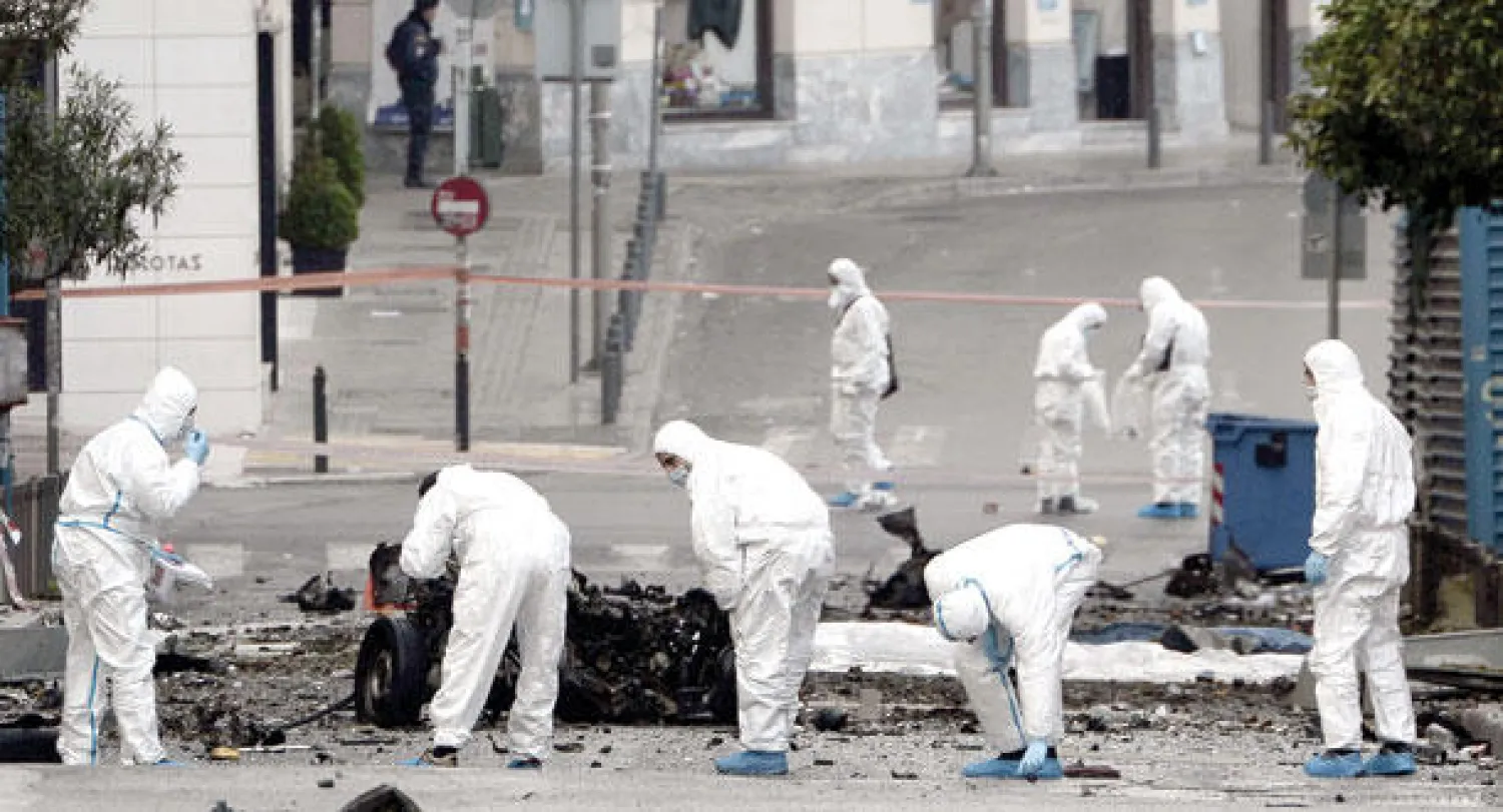 محققون يبحثون عن أدلة وسط حطام السيارة المفخخة قرب بنك اليونان في أثينا أمس (أ.ف.ب)