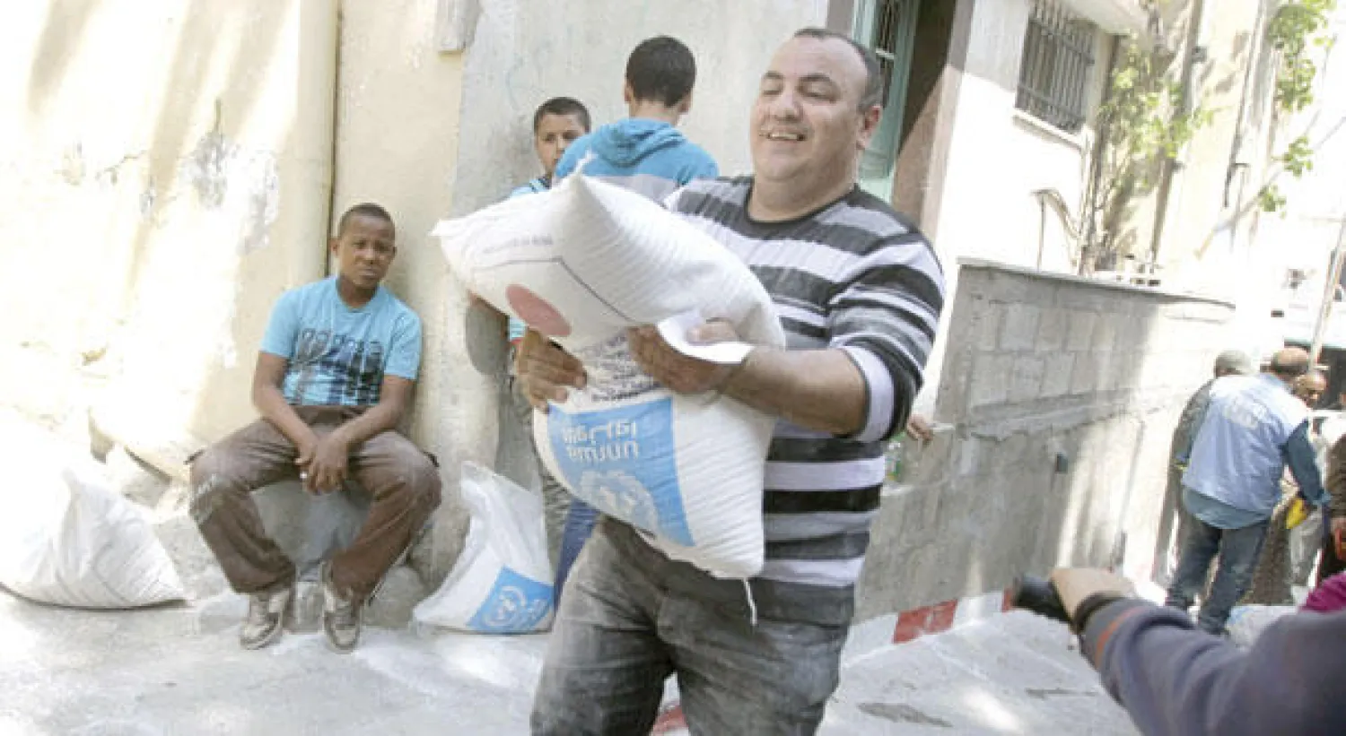 فلسطيني يحمل كيسا من الدقيق من مساعدات وزعتها «الأونروا» في مخيم جنين بالضفة الغربية (أ.ب)