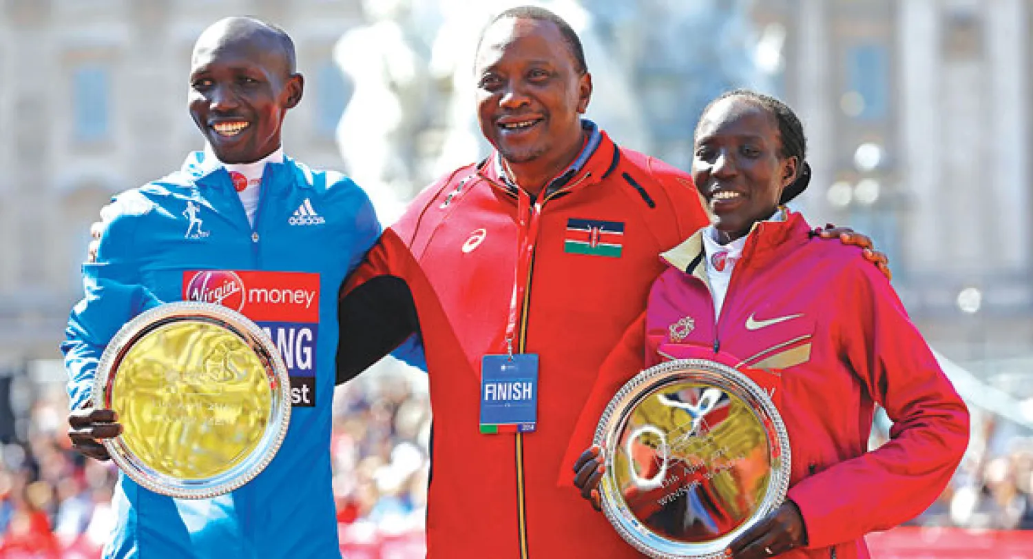 الرئيس الكيني كينياتا الذي حضر ماراثون لندن يتوسط كيبسانغ وكيبلاغات الفائزين بلقبي الرجال والسيدات  (رويترز)