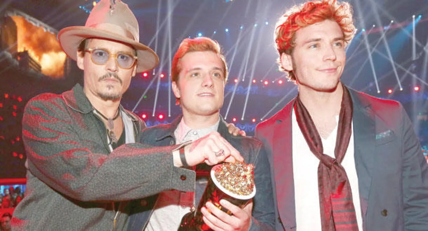 الممثل جوني ديب يسلم جوش هوتشرسن وجون كلافلين جوائزهما عن فيلم ألعاب الجوع (أ.ف.ب)