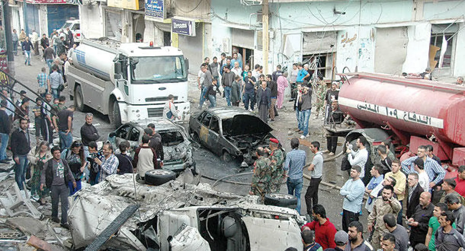 سوريون يعاينون الدمار الذي خلفه انفجار سيارة مفخخة في حمص أمس (أ.ف.ب)
