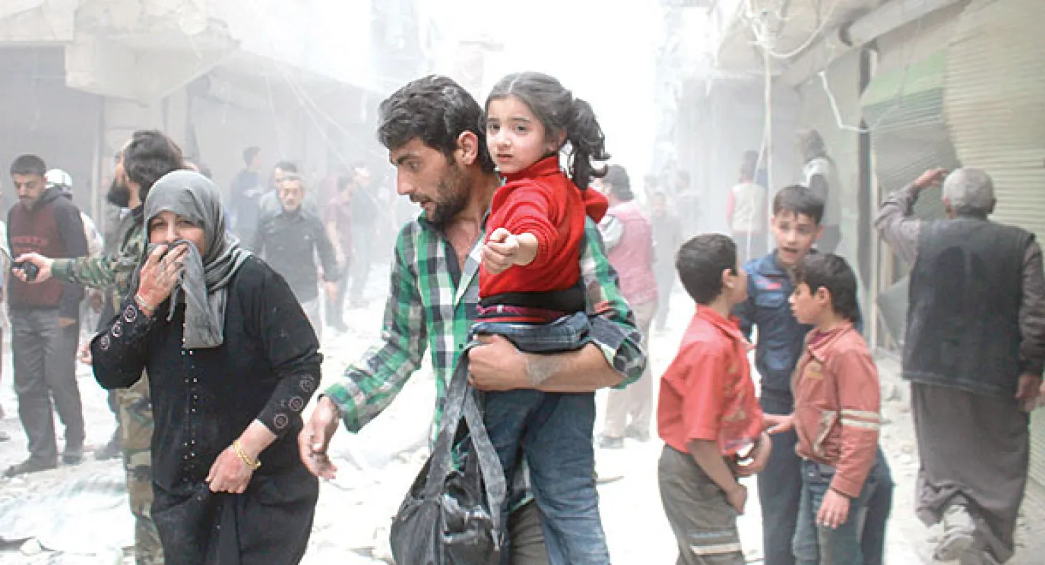 عائلة سورية تفر بعد غارة جوية شنها طيران النظام السوري استهدفت مباني في حي الأنصاري بحلب أمس (أ.ف.ب)