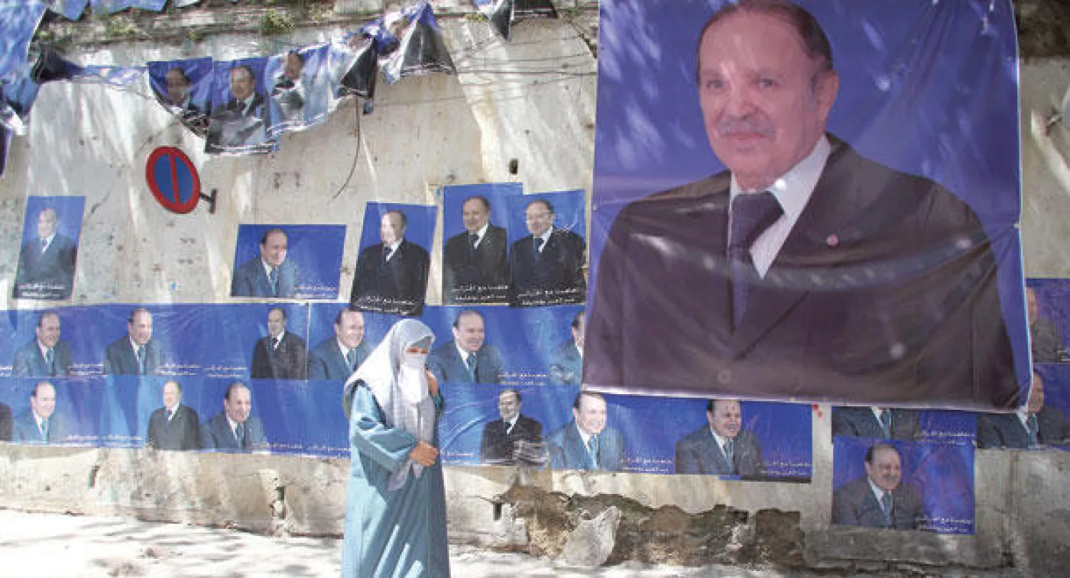 جزائرية تمر أمس في العاصمة بجانب ملصق دعائي للرئيس عبد العزيز بوتفليقة للانتخابات الرئاسية المزمع إجراؤها اليوم (إ. ب. أ)