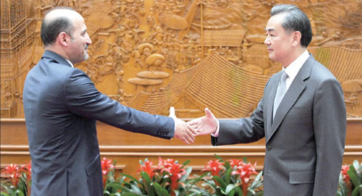 زعيم المعارضة السورية أحمد الجربا ووزير الخارجية الصيني بانغ يي لدى لقائهما في بكين أمس (أ.ف.ب)