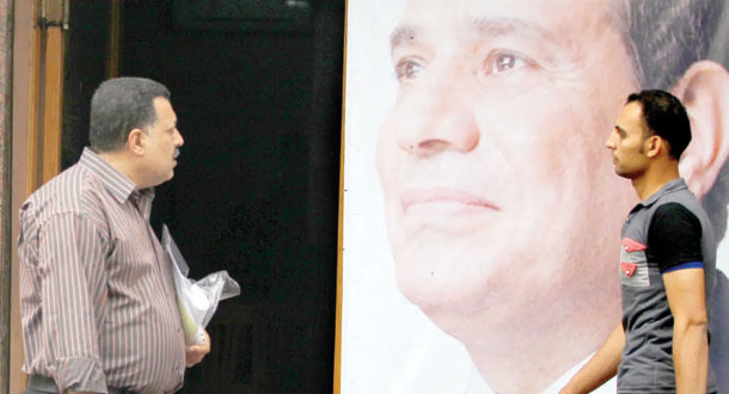 مصريان يمران أمام ملصقات دعائية على جدار أحد مراكز حملة المرشح الرئاسي عبد الفتاح السيسي في القاهرة أمس (رويترز)