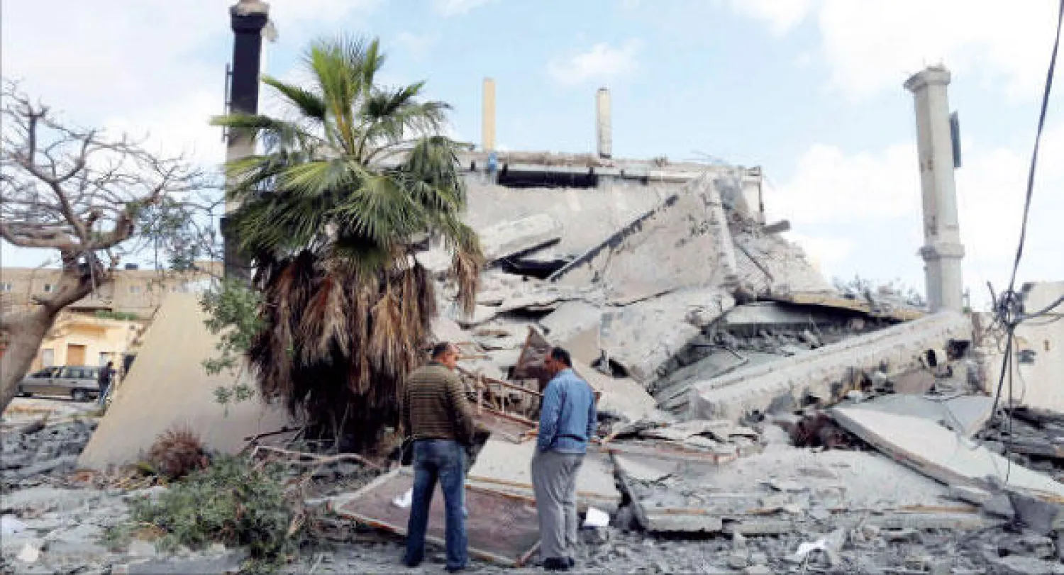 ليبيان يتفقدان مبنى كان تابعا للقوات الحكومية قبل تفجيره من قبل جهة مجهولة في بنغازي أمس (رويترز)