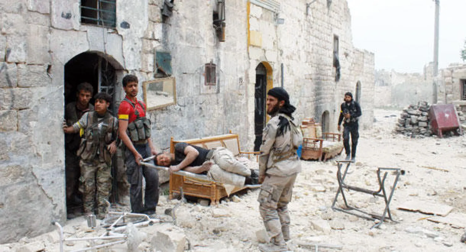 مقاتلون سوريون ينقلون جريحا لإسعافه بعد إصابته أثناء مواجهات مع قوات النظام في حلب أمس (أ.ف.ب)