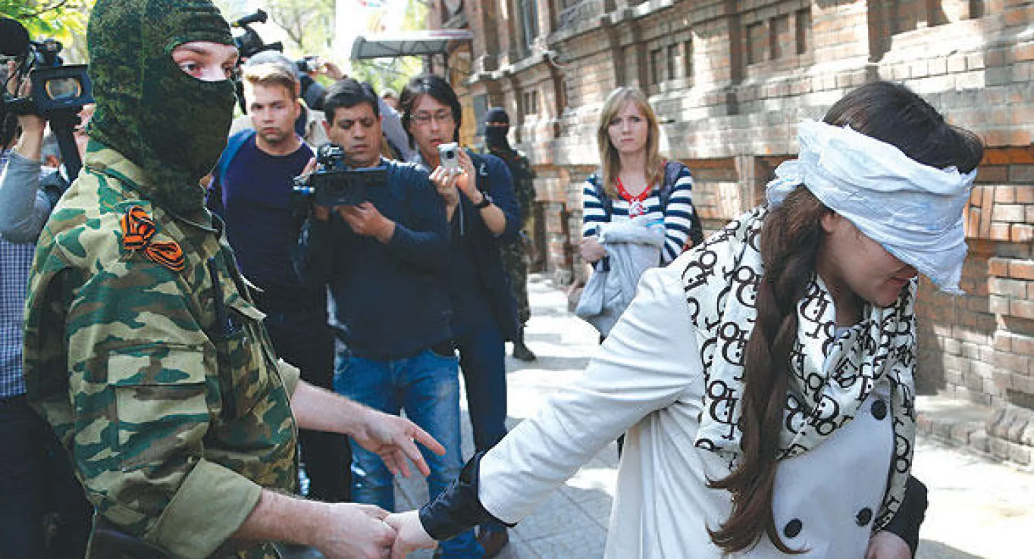 الصحافية والناشطة إيرما كرات معصوبة العينين عقب احتجازها على أيدي عدد من المتشددين  يرتدون الملابس العسكرية  في مدينة سلافيانسك الأوكرانية أمس (أ.ب)