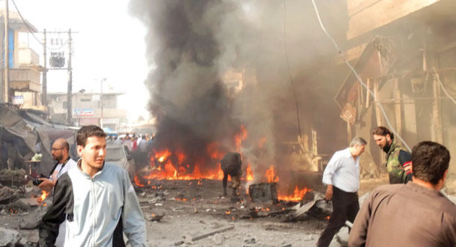 سوريون يتفحصون آثار القصف بالبراميل المتفجرة على مدينة الأتارب بريف حلب (رويترز)