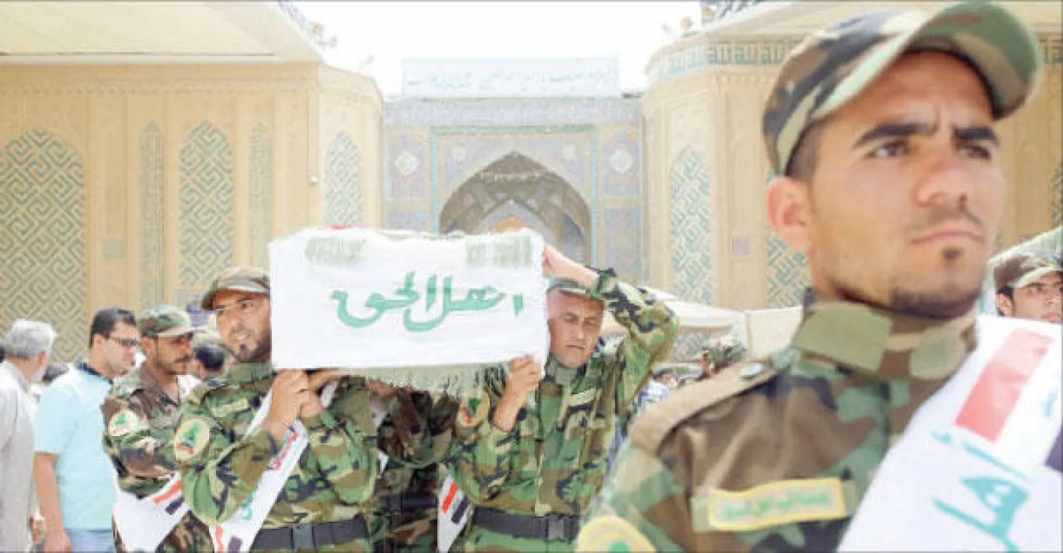 عناصر في جماعة عصائب أهل الحق يشيعون في النجف أمس أحد رفاقهم الذين قتلوا في تفجير انتحاري استهدف تجمعا انتخابيا للجماعة في بغداد أول من أمس (رويترز)