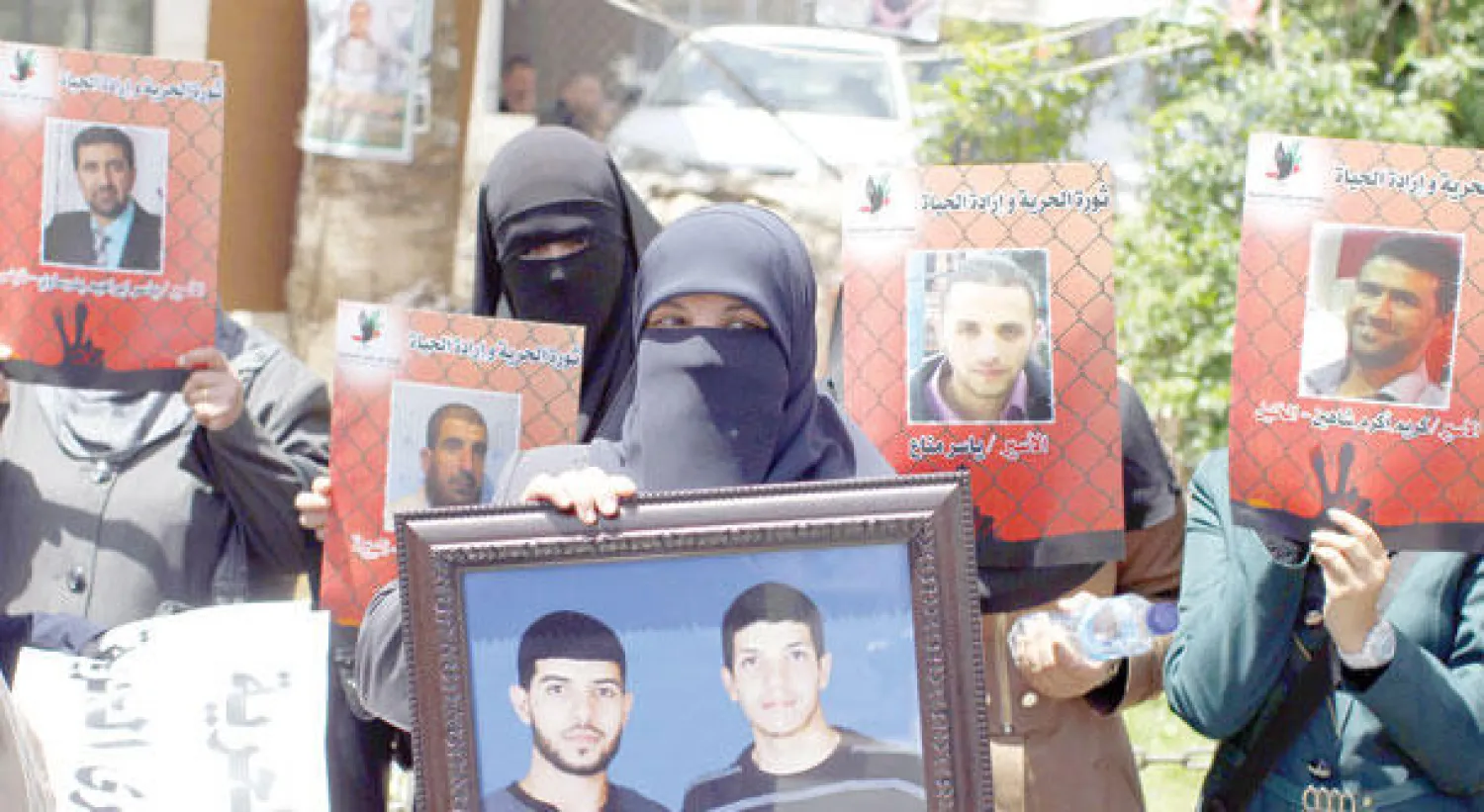 فلسطينيات يرفعن صور أبنائهن المعتقلين في سجون الاحتلال في مدينة رام الله أمس (أ.ف.ب)