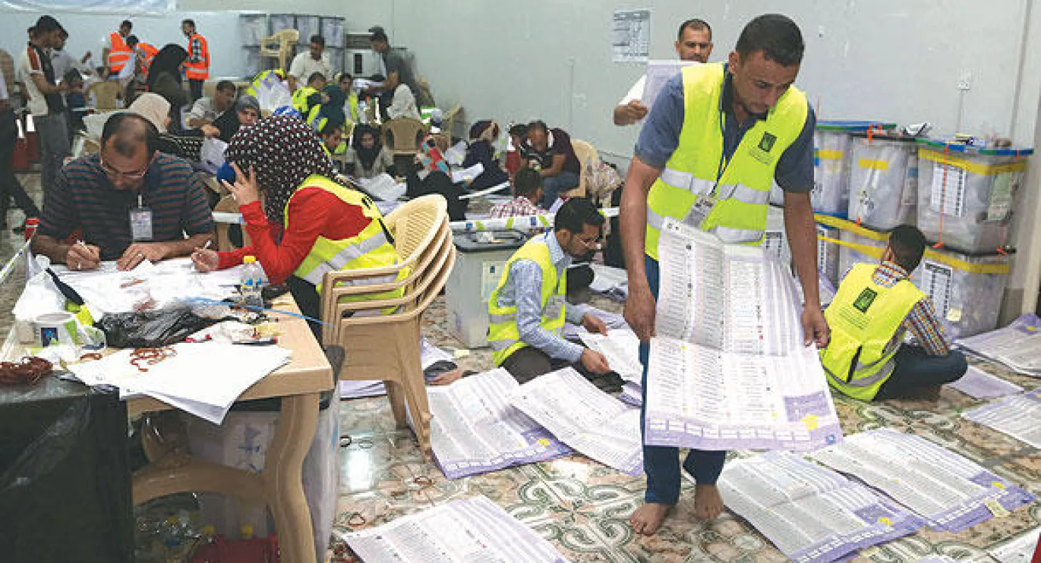 عاملون في هيئة الانتخابات العراقية يواصلون عد أصوات الناخبين في مركز للانتخاب في البصرة (أ.ب)