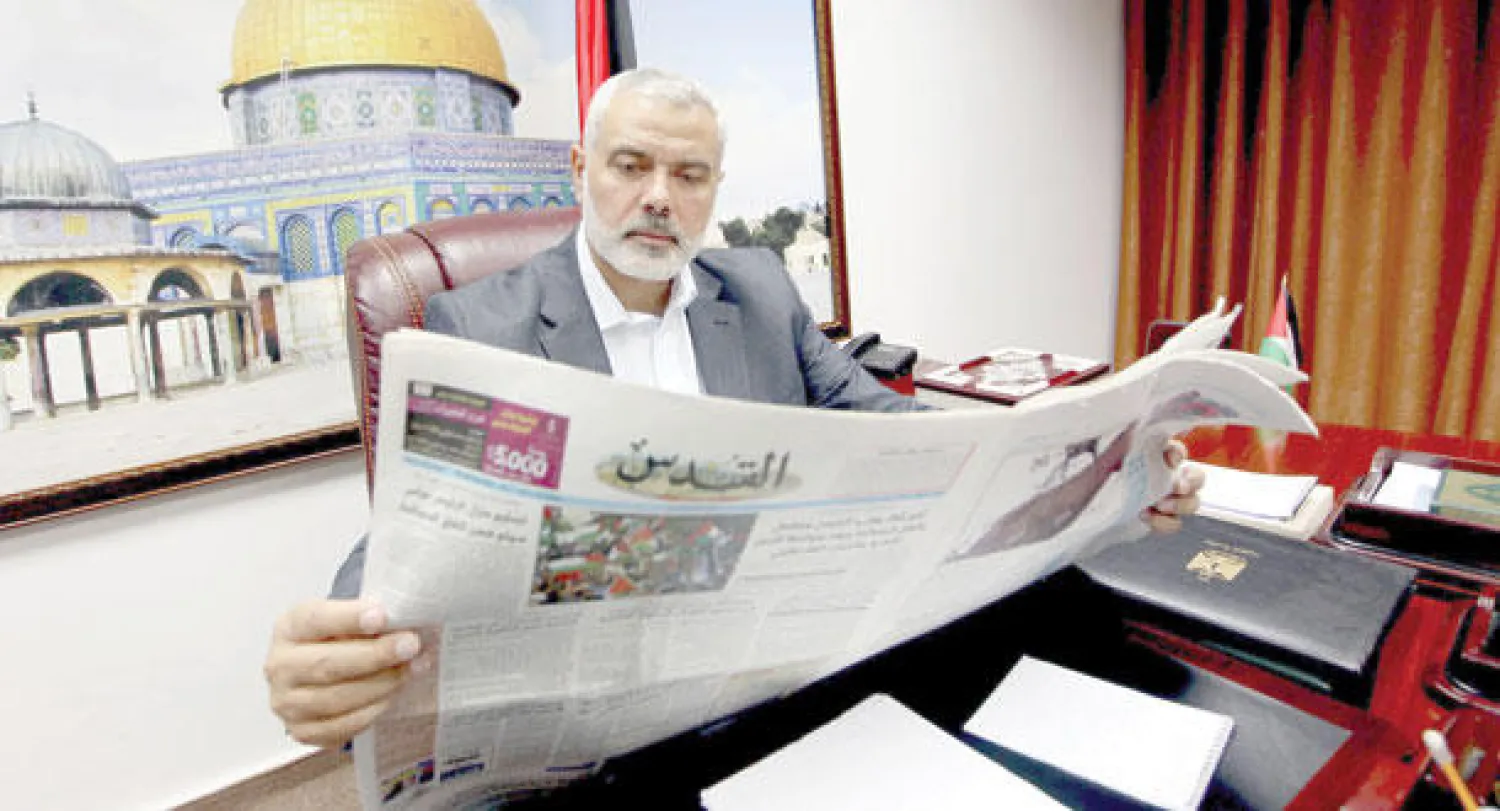 إسماعيل هنية رئيس حكومة غزة المقالة يطالع صحيفة «القدس»، المقربة من السلطة والتي عاودت الصدور في غزة، أمس، لأول مرة منذ حجبها في القطاع عام 2007 (رويترز)