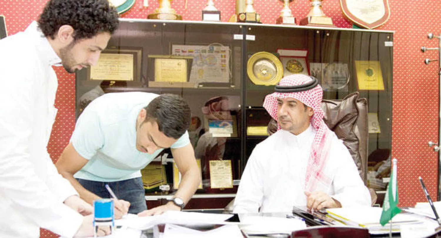 صالح العمري أثناء توقيعه عقد الانتقال للأهلي