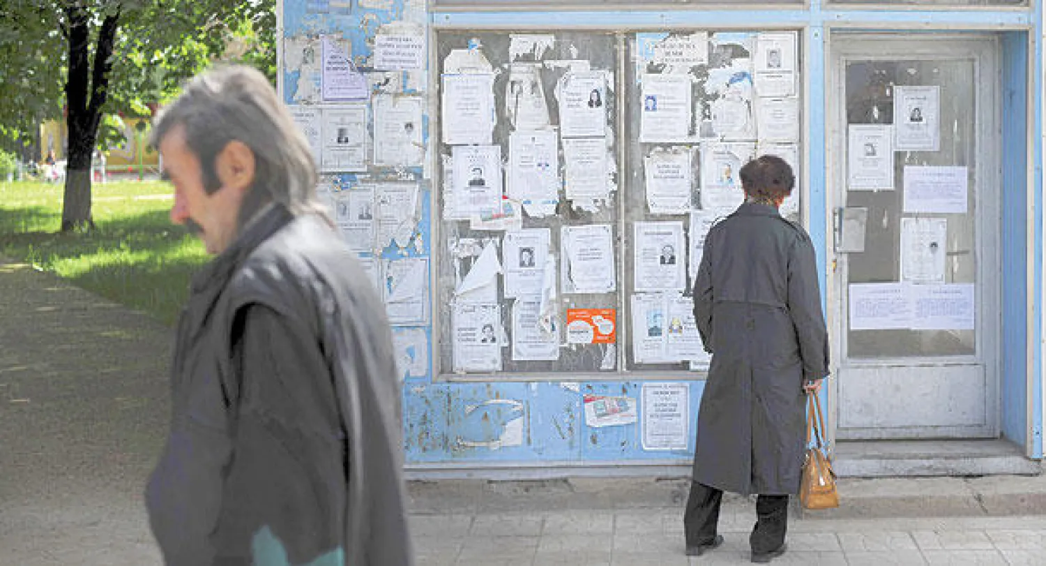 امرأة تنظر إلى إشعارات النعي على جدار مكتب حكومي سابق في راسوفو (شمال صوفيا)  التي تعد أفقر منطقة في أوروبا (أ.ف.ب)