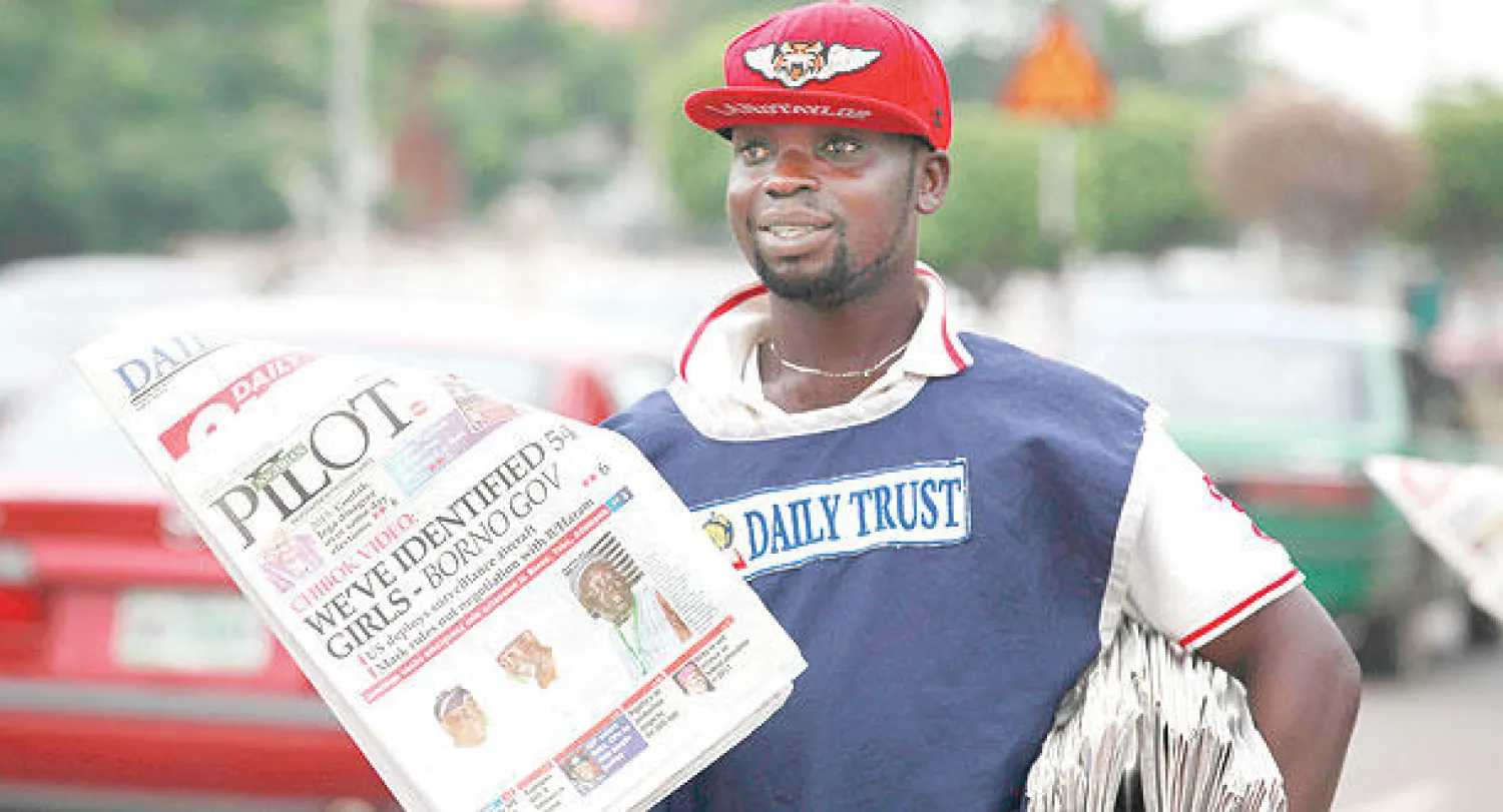 شاب يبيع في شارع بأبوجا أمس صحفا وضعت على صدر صفحاتها الأولى خبر التعرف على 54 من الفتيات المخطوفات بعد بث {بوكو حرام} شريط فيديو جديدا لهم الاثنين الماضي (أ.ب)