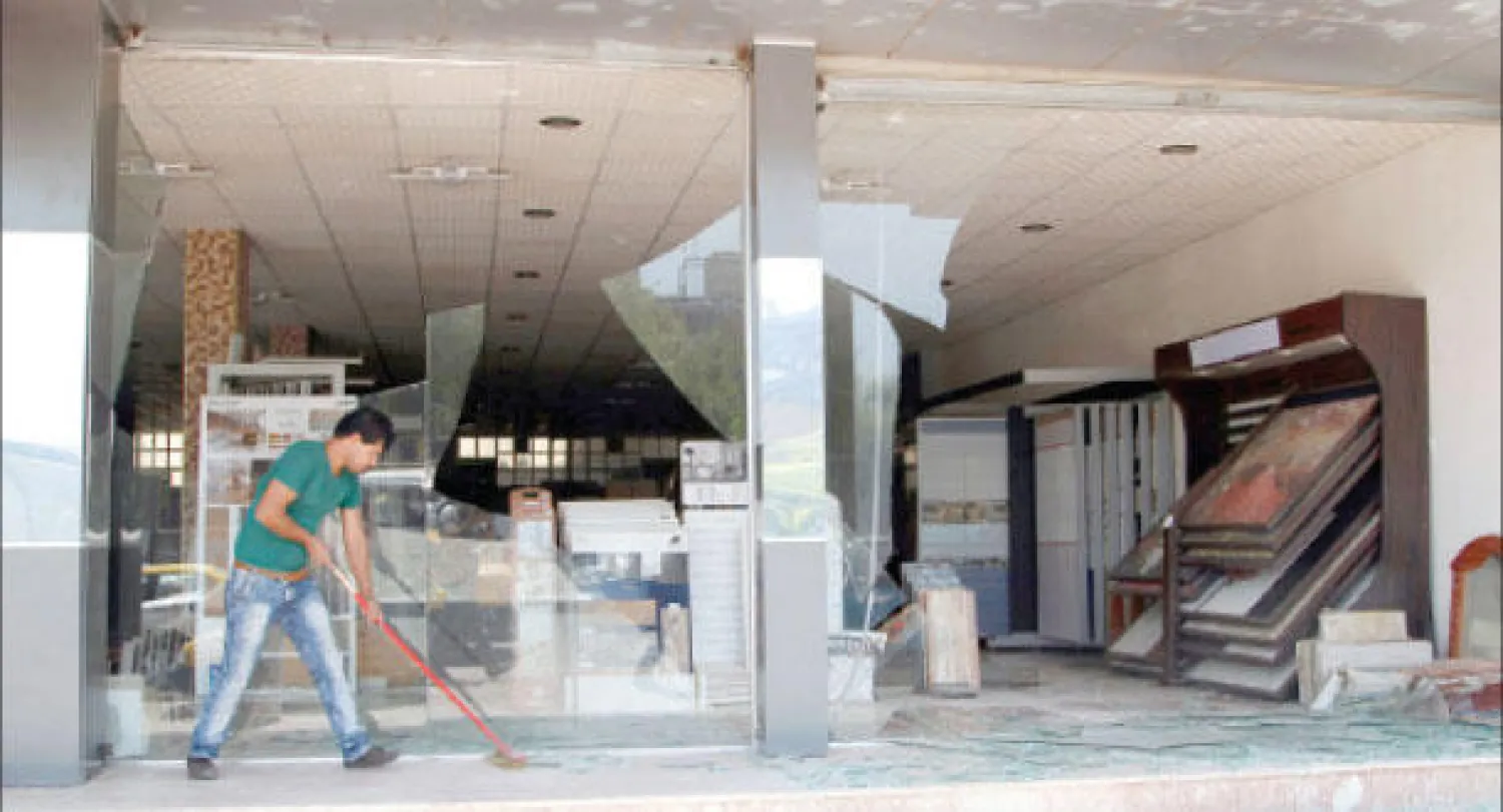 عراقي يزيح آثار الدمار عن محله التجاري التي تسببت بها تفجيرات انتحارية في الكرادة أمس (رويترز)