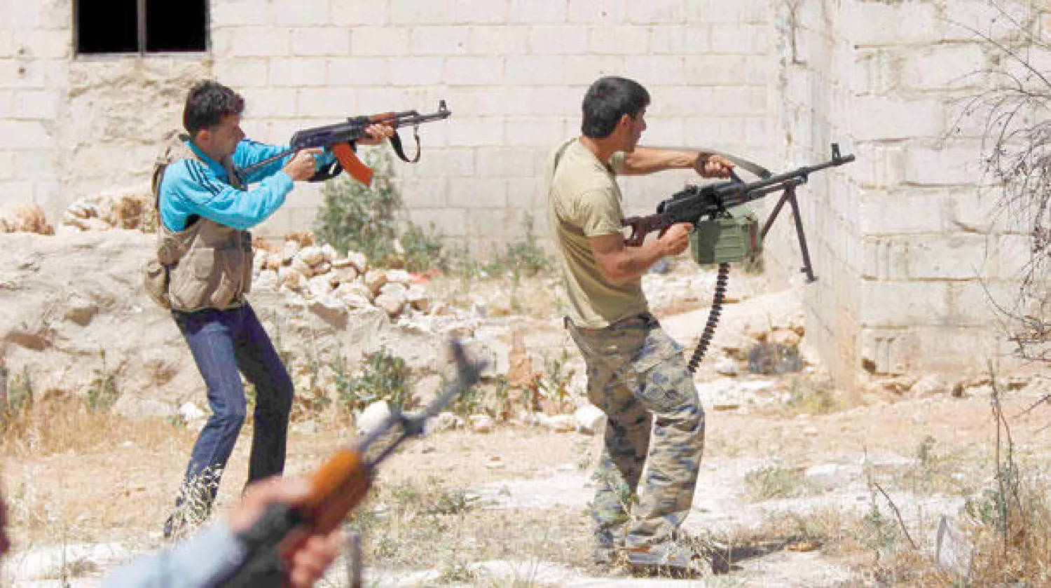 عناصر من الجيش السوري الحر يوجهون نيران بنادقهم باتجاه قوات النظام في محيط مدينة إدلب أمس (رويترز)