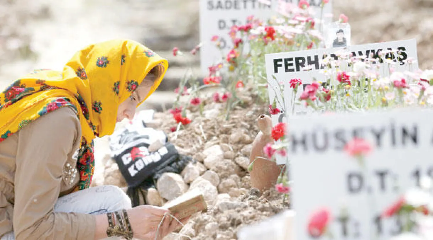 تركية تتلو آيات من القرآن الكريم في مقبرة خصصت لضحايا كارثة منجم سوما أمس (إ.ب.أ)