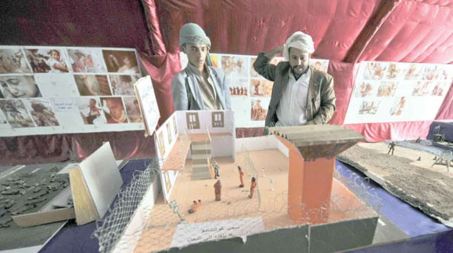 يمنيان ينظران إلى مجسم سجن غوانتانامو في صنعاء أمس (إ.ب.أ)