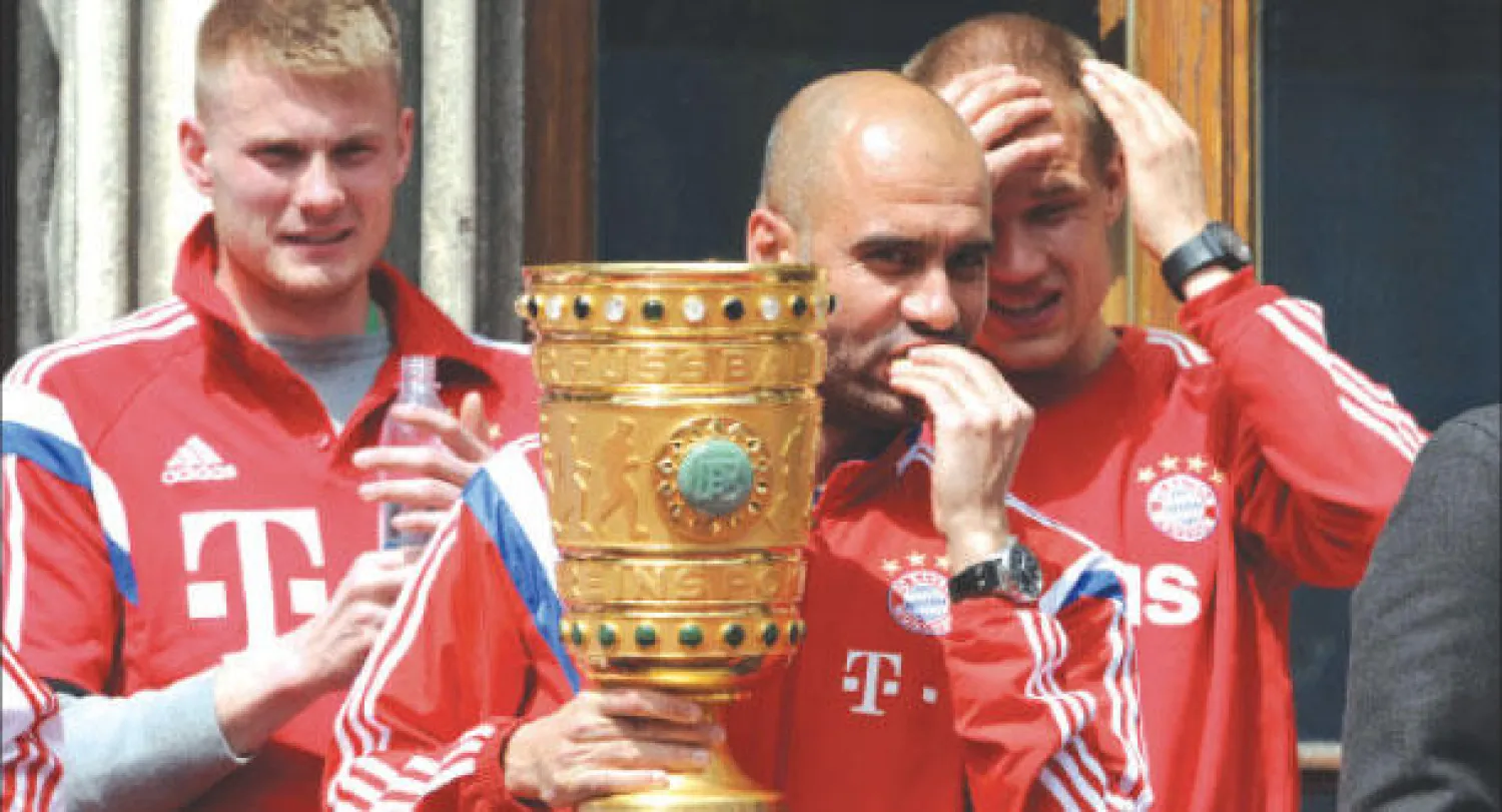 غوارديولا يحمل كأس ألمانيا محتفلا مع لاعبيه أمام جماهير البايرن (أ.ف.ب)