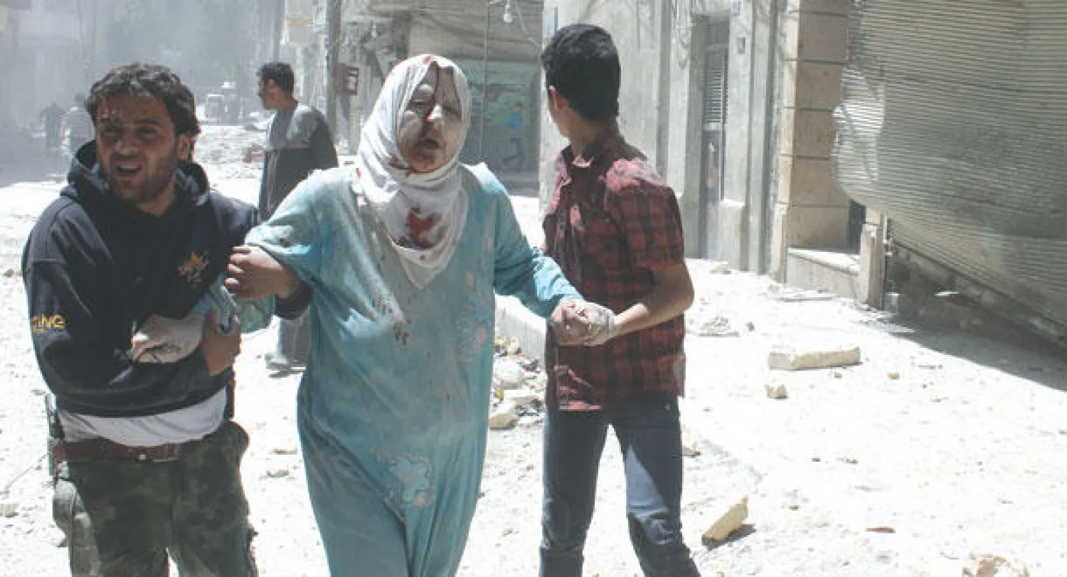 سوريان يساعدان امرأة أصيبت جراء غارة للقوات النظامية استهدفت حي القاطرجي في حلب أمس (أ.ف.ب)