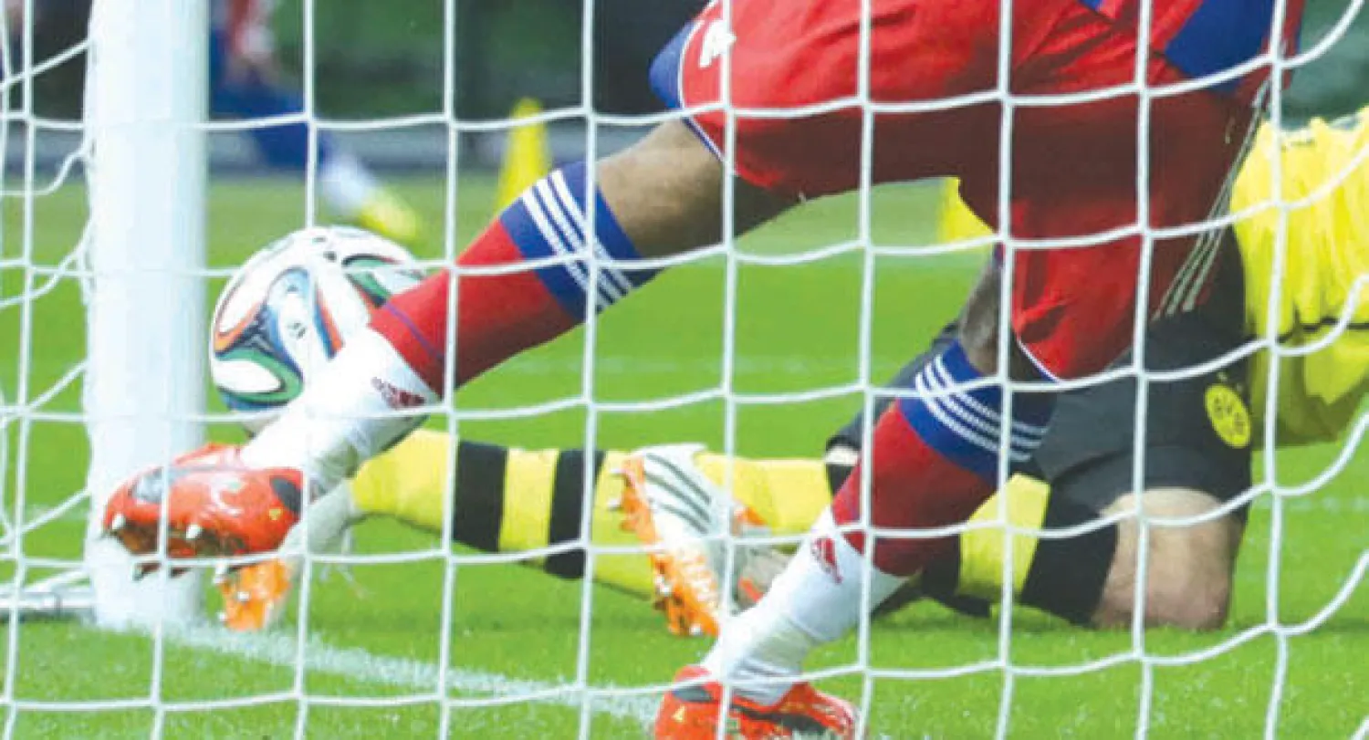 دانتي لاعب بايرن ميونيخ يشتت الكرة بعد أن تجاوزت خط المرمى دون أن يحتسبها الحكم هدفا لدورتموند (رويترز)