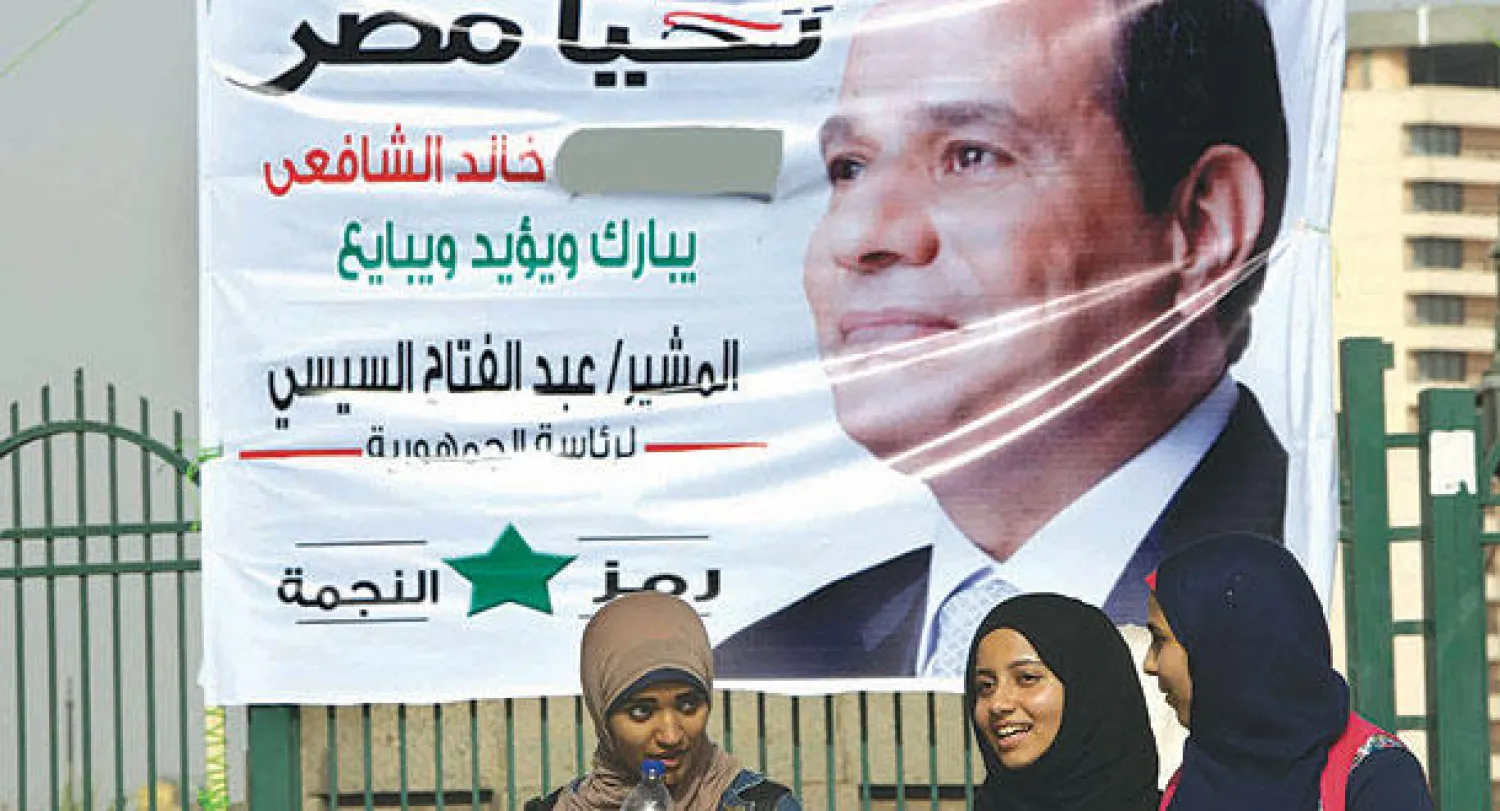 مصريات يمررن بالقرب من ملصق انتخابي ضخم يؤيد المشير عبد الفتاح السيسي وسط القاهرة أمس (أ.ب)
