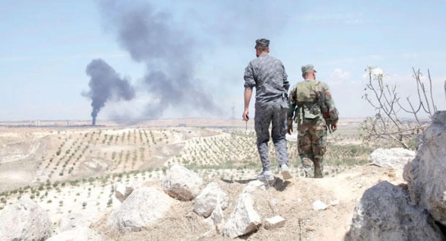 جنديان تابعان للقوات النظامية السورية يسيران في منطقة هضبة الهيلان بعد قصفها واستعادتها من مقاتلي المعارضة أمس (رويترز)