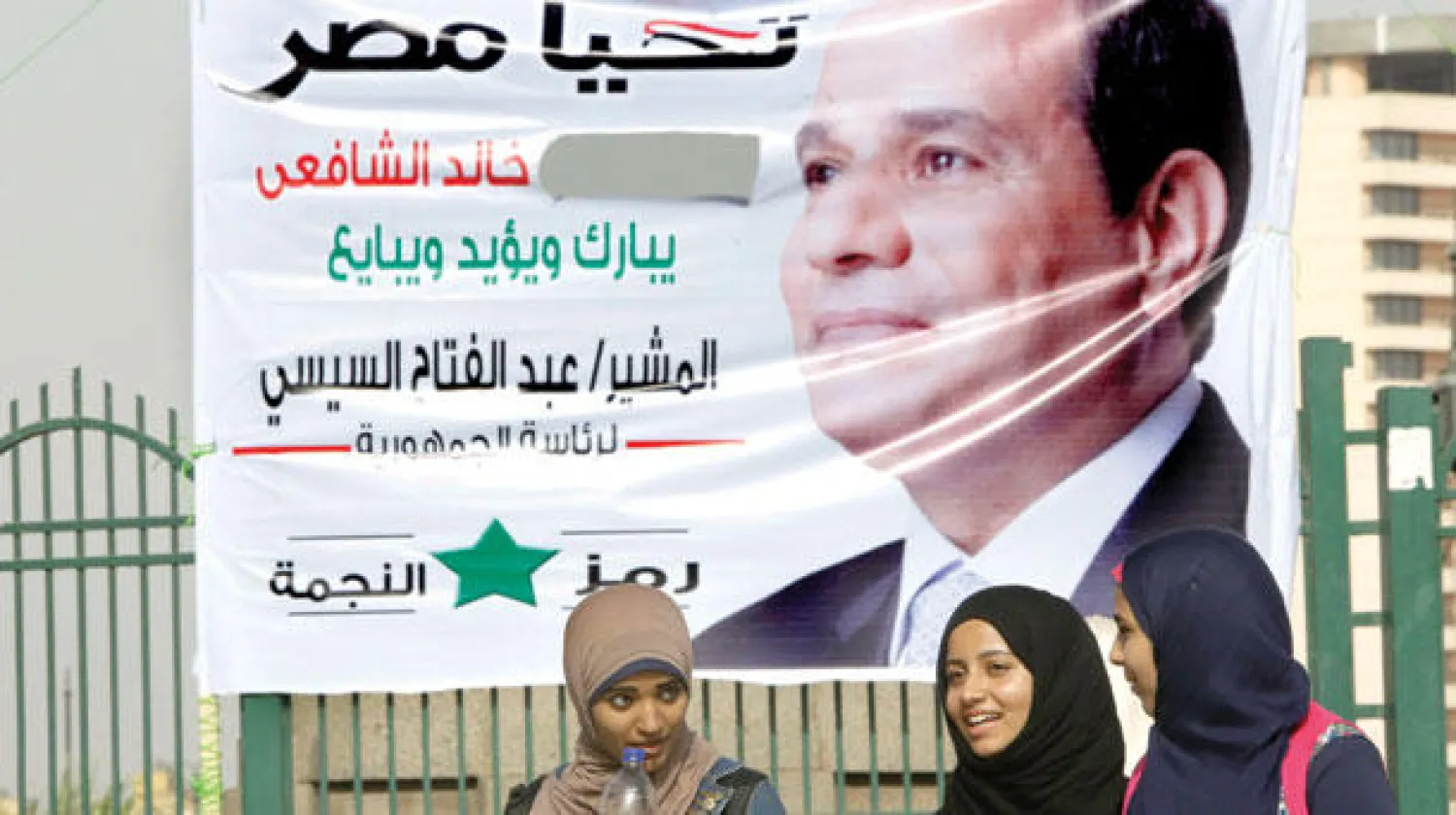 فتيات مصريات يسرن أسفل ملصق دعائي يحمل صورة المشير عبد الفتاح السيسي المرشح الرئاسي المصري وسط القاهرة أمس (أ.ب)