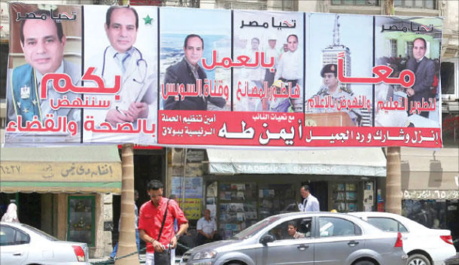 مواطن مصري يمر أسفل ملصقات للمشير عبد الفتاح السيسي بالقرب من ميدان التحرير أمس (رويترز)