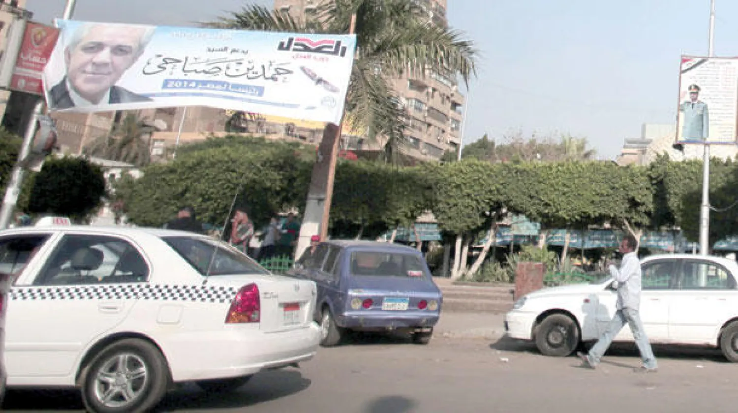 مصريون يمرون تحت ملصق دعائي لحمدين صباحي المرشح الرئاسي بوسط القاهرة أمس (أ.ب)