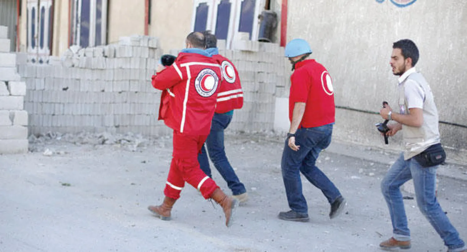 أفراد من الصليب الأحمر يلجأون إلى مكان آمن إثر قصف قوات النظام مدينة دوما (أ.ف.ب)