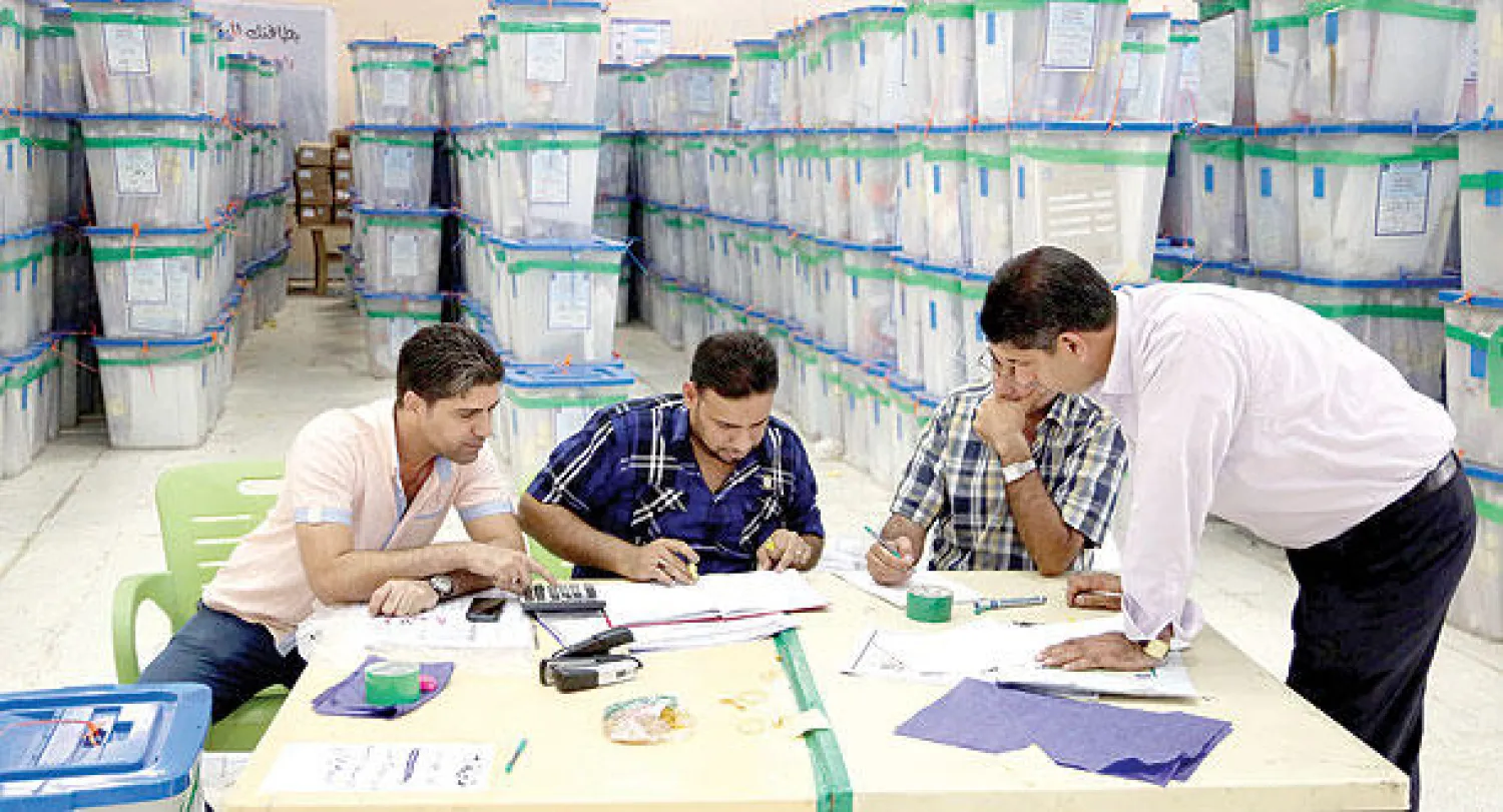 موظفو المفوضية العليا المستقلة للانتخابات خلال عمليات العد والفرز اليدوي للأصوات في بغداد (أ.ب)