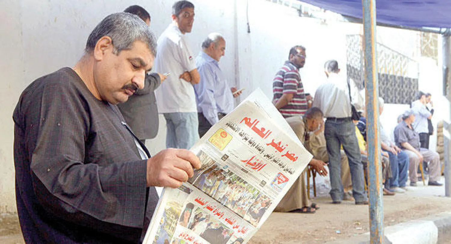 مصري يطالع صحيفة محلية أمام إحدى اللجان أمس في انتخابات يبحث فيها أغلب المواطنين عن الاستقرار (أ.ب)