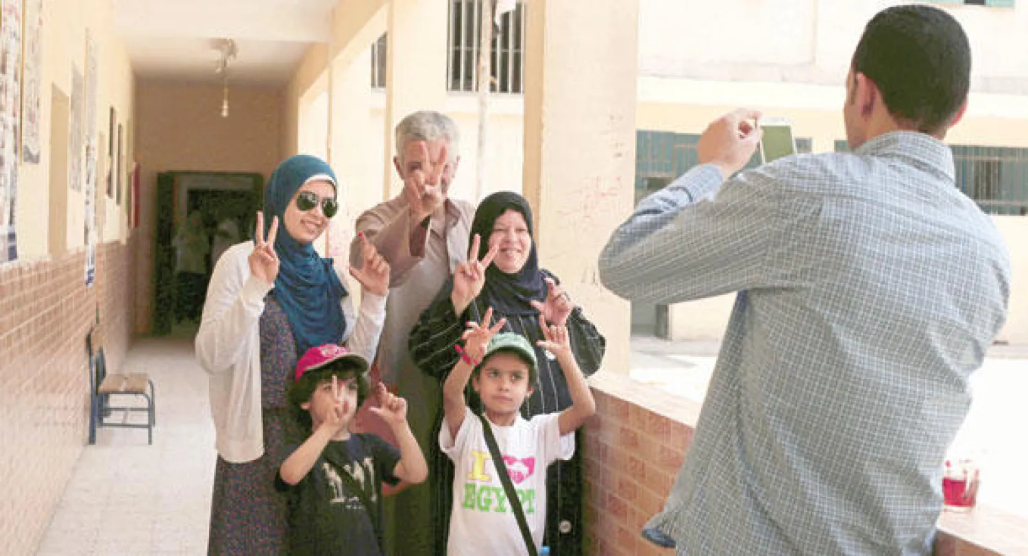 أحد موظفي لجنة اقتراع بالقاهرة يلتقط صورة تذكارية لأسرة مصرية عقب إدلائها بأصواتها أمس (أ.ب)