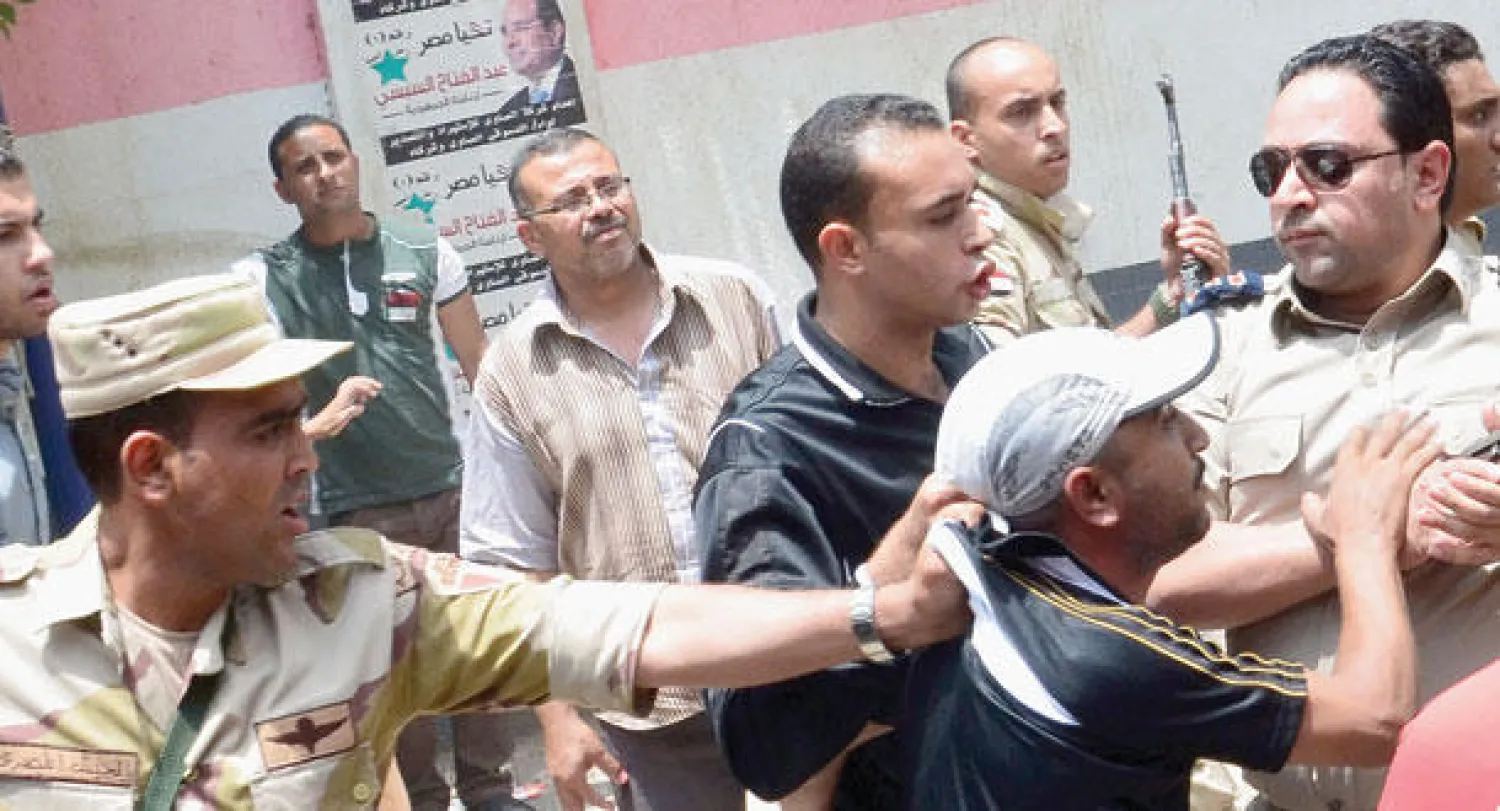 عناصر من القوات المسلحة تلقي القبض على رجل عقب إطلاقه رصاصات في محيط إحدى اللجان في مدينة المنصورة شمال القاهرة أمس (أ.ف.ب)