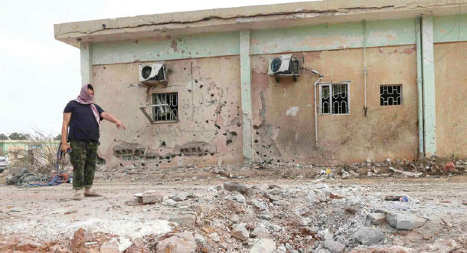 عنصر تابع لكتيبة 17 فبراير يشير إلى الدمار الذي خلفته طائرتان تابعتان لقوات حفتر في بنغازي أمس (رويترز)