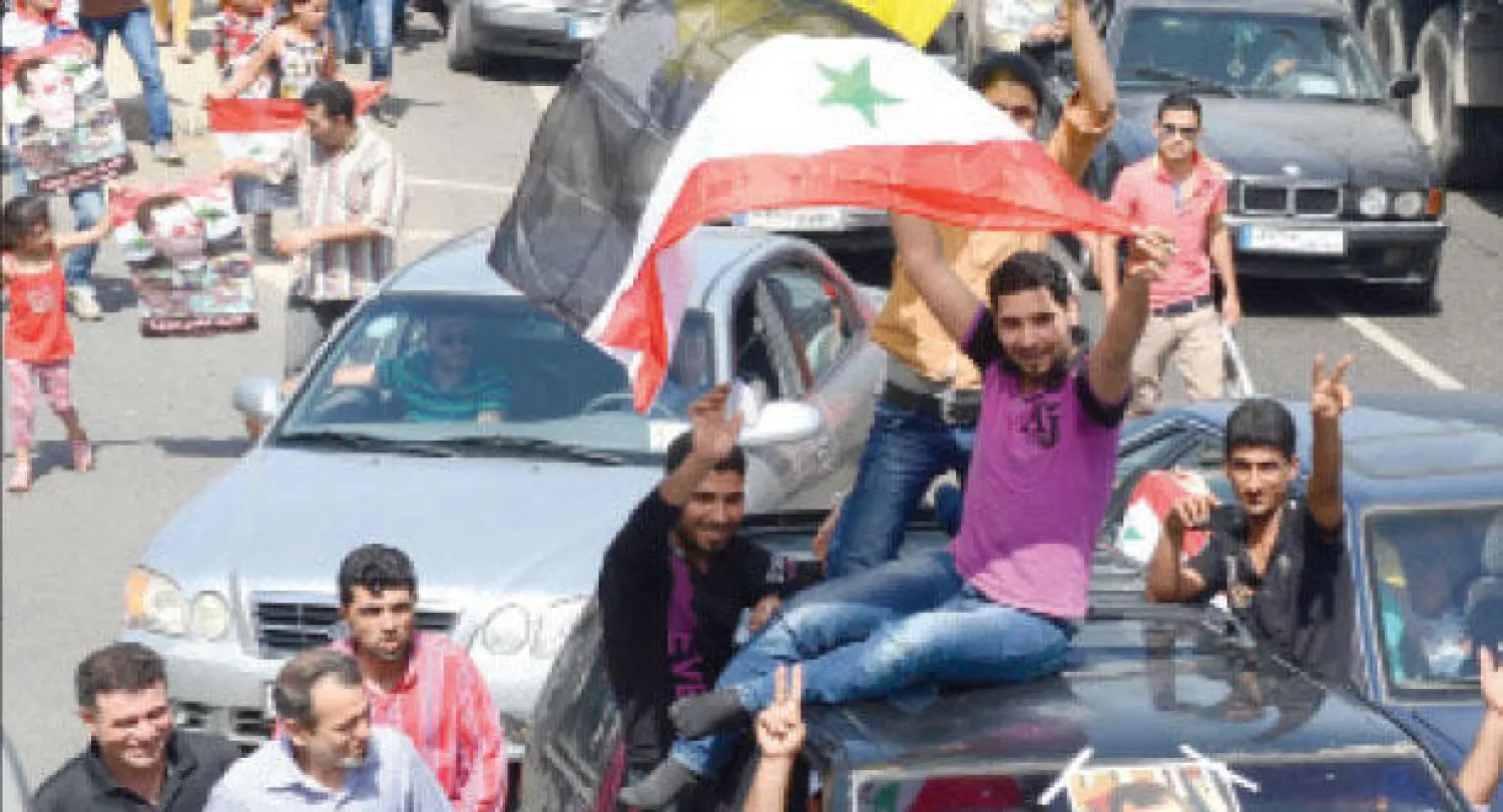 سوريون مؤيدون للأسد يتوجهون إلى سفارة بلادهم في لبنان للإدلاء بأصواتهم، رافعين صورا للأسد وعلم بلادهم ورايات حزب الله (تصوير: نبيل إسماعيل)