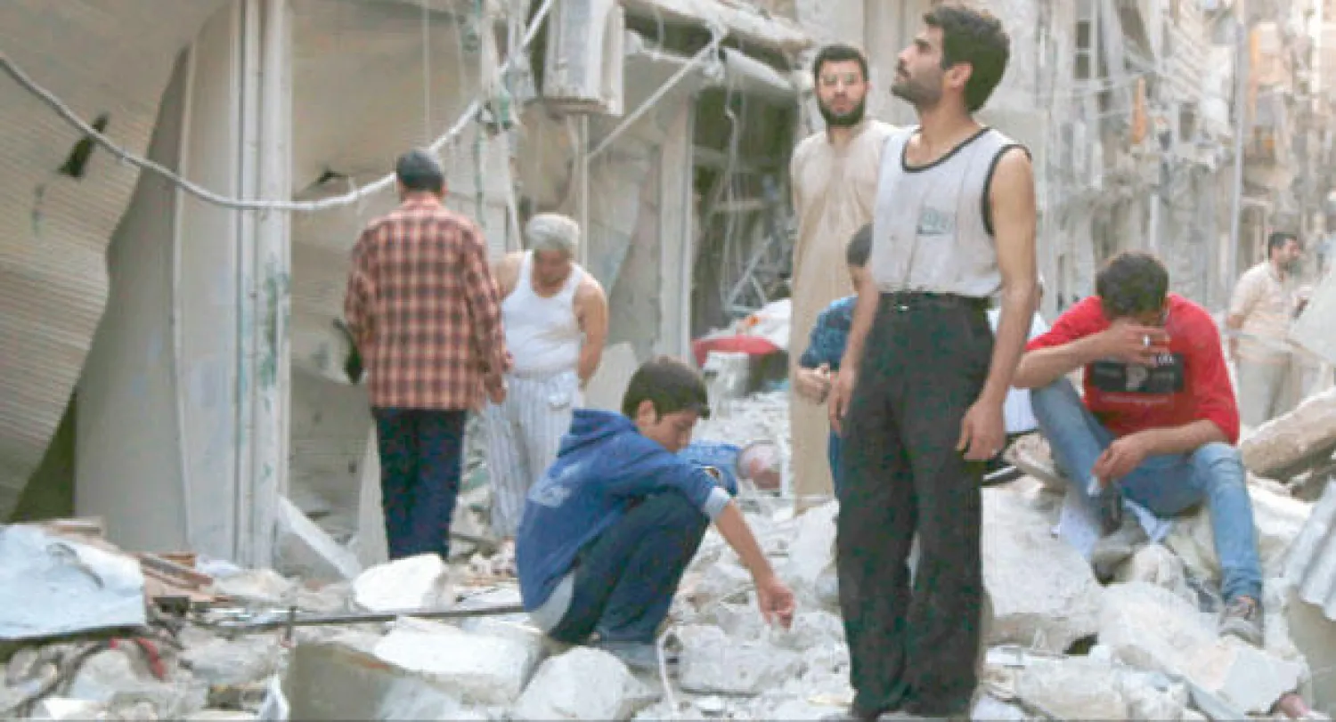 سوريون يعاينون الدمار الذي الحقته البراميل المتفجرة في حلب أمس (رويترز)