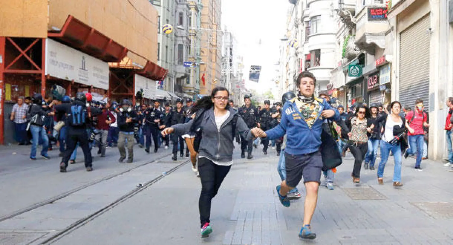 الشرطة التركية تطارد شبابا في شارع الاستقلال القريب من ساحة تقسيم وسط إسطنبول أمس (إ.ب.أ)